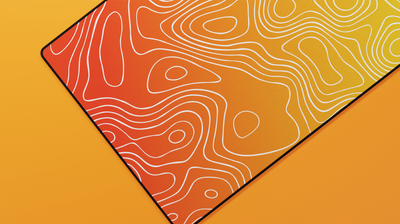 Close-up of the left side of the Amber Topography Deskmat featuring vibrant orange tones, precise stitching, and soft neoprene texture.