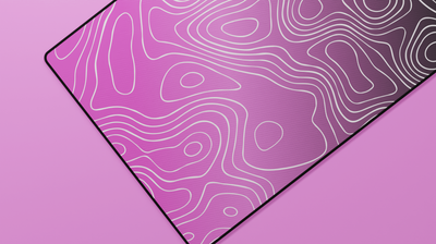 Close-up of the left side of the Blink Topography Deskmat highlighting soft pink tones, detailed topographic lines, and stitched edge texture.