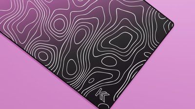 Close-up of the right side of the Blink Topography Deskmat showing deep black tones blending with pink gradient and clean neoprene stitching.