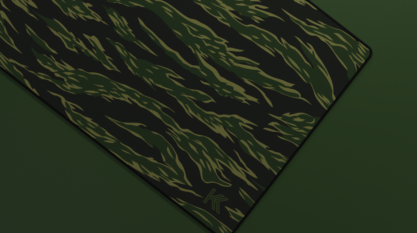 Close-up of the right side of the Forest Tiger Camo Deskmat showing bold stripe pattern, hemmed stitching, and surface texture.