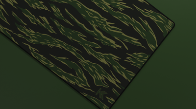 Close-up of the right side of the Forest Tiger Camo Deskmat showing bold stripe pattern, hemmed stitching, and surface texture.