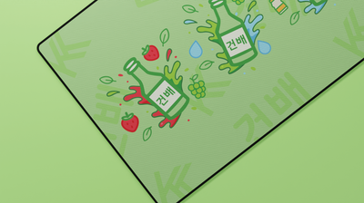 Close-up of the Korean Soju Flavors Deskmat showing soju bottle and strawberry illustrations with soft neoprene surface and hemmed stitching.