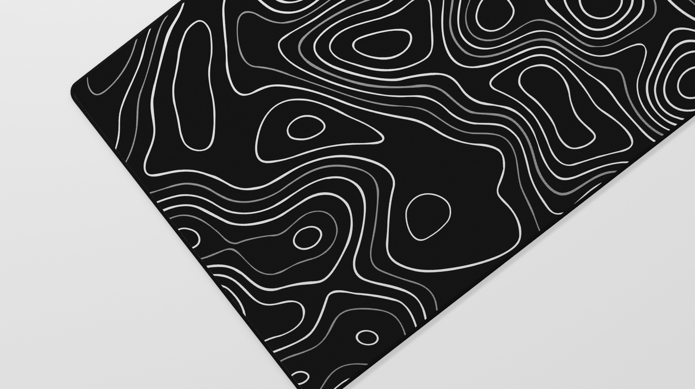 Close-up of the left side of the Obsidian Topography Deskmat showing gray topographic lines against a deep black neoprene surface.
