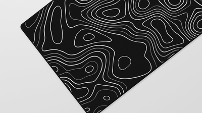Close-up of the left side of the Obsidian Topography Deskmat showing gray topographic lines against a deep black neoprene surface.
