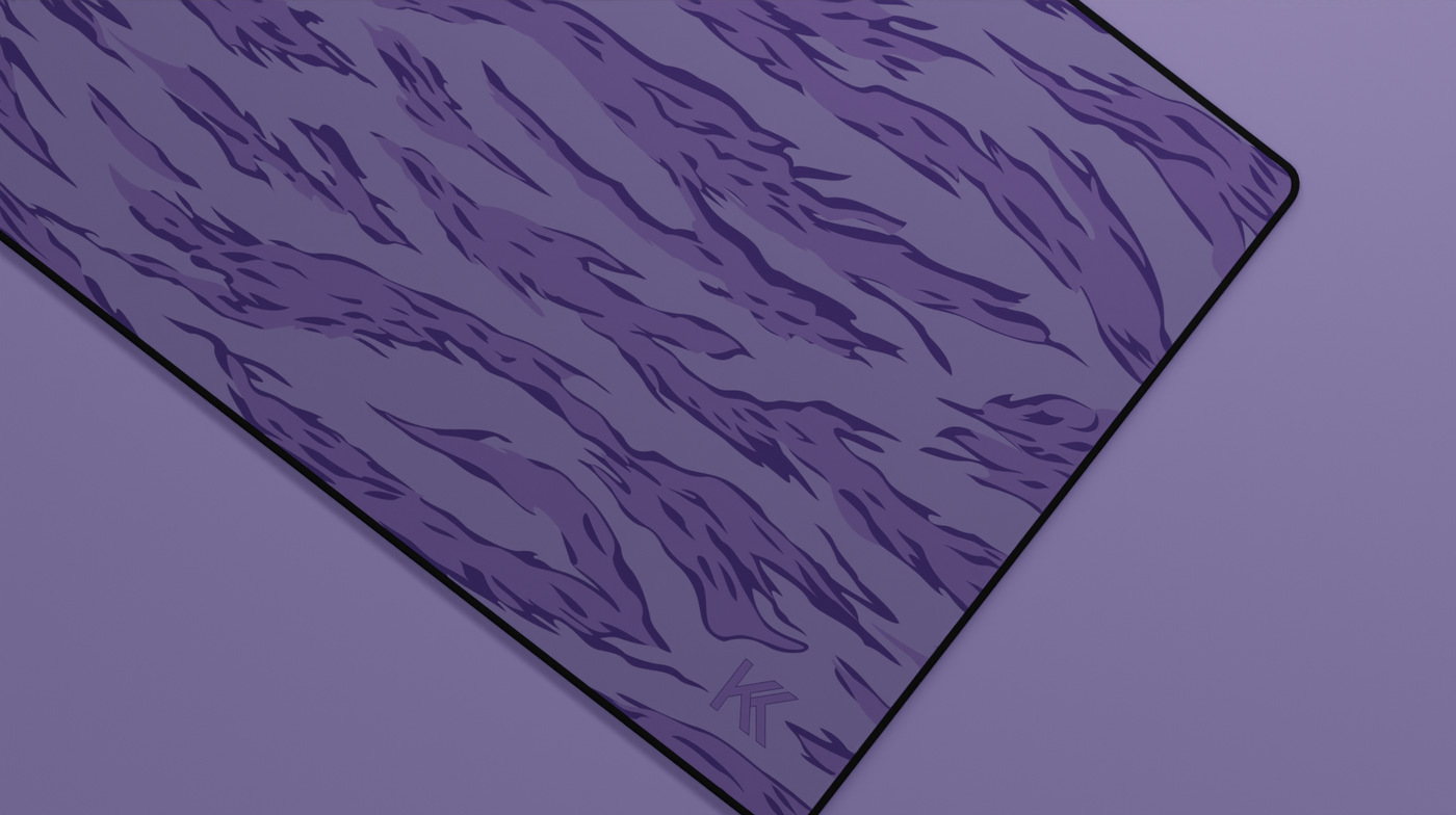 Close-up of the right side of the Purple Tiger Camo Deskmat showing bold stripe pattern, hemmed stitching, and surface texture.