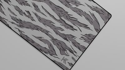 Close-up of the right side of the Winter Tiger Camo Deskmat showing bold stripe pattern, hemmed stitching, and surface texture.
